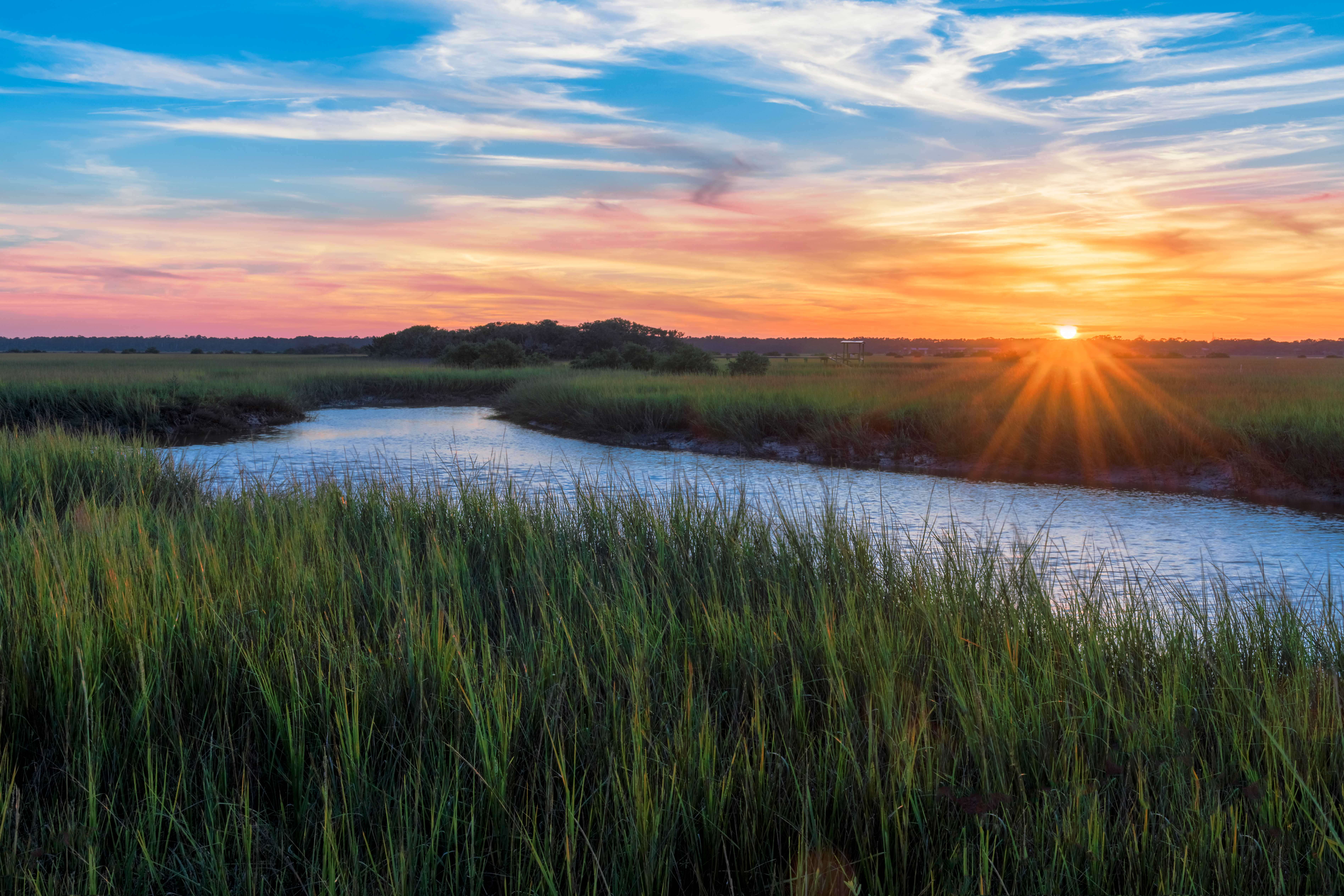 Sunset over field with a river running through 